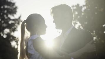 Posing of the newlyweds. Action.A beautiful young couple with a blonde girl in big earrings and her husband with a beard who are sitting and hugging on the street and the bright rays of the sun are photo