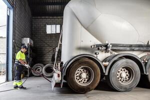 Serious male mechanic using hydraulic jack to lift truck in garage photo