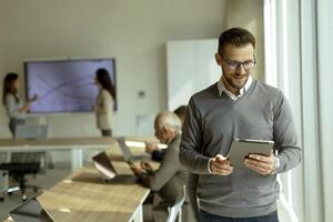 Young modern businessman using digital tablet in the office photo