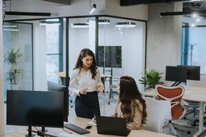 Young business women discussing in cubicle at the office photo