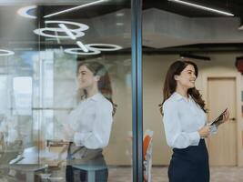 Young woman with digital tablet walking in the modern office hallway photo