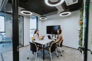 Young business women discussing in cubicle at the office photo