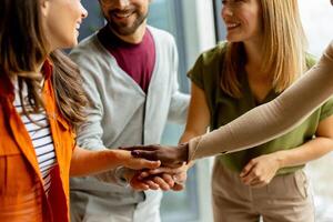 Young multiethnic startup team hold hands together in the modern office photo