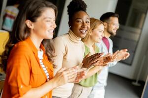 Young multiethnic startup team standing and applauding in the modern office photo