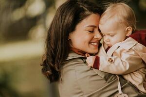 Young woman holding cute baby girl in the autumn park photo