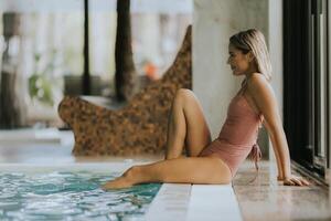 Young woman relaxing by the indoor swimming pool photo