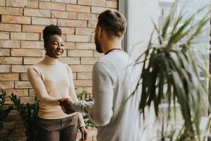 Young multiethnic business couple handshaking in the modern office photo