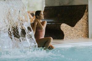 joven mujer relajante por el interior nadando piscina foto