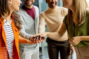 Young multiethnic startup team hold hands together in the modern office photo