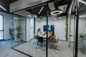 Young business women discussing in cubicle at the office photo