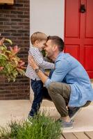 Father and his son have a good time in front of house door photo