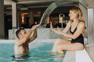 joven Pareja teniendo divertido en el interior nadando piscina foto