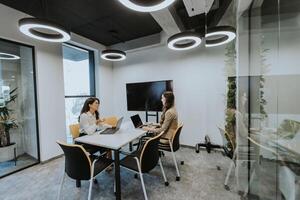 Young business women discussing in cubicle at the office photo