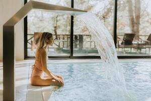 joven mujer relajante por el interior nadando piscina foto