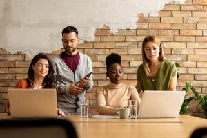 Young multiethnic startup team working by the brick wall in the industrial style office photo