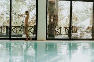 joven mujer caminando por el interior nadando piscina foto