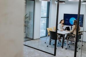 Young business women discussing in cubicle at the office photo