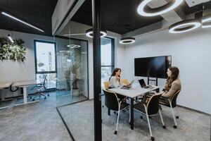 Young business women discussing in cubicle at the office photo