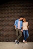 Smiling young couple in love in front of house brick wall photo