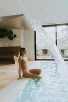 Young woman relaxing by the indoor swimming pool photo