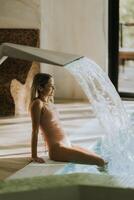 Young woman relaxing by the indoor swimming pool photo