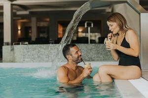 Young couple relaxing by the indoor swimming pool photo