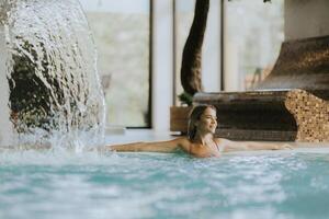 joven mujer relajante en el interior nadando piscina foto