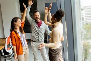 Young multiethnic startup team hold hands together in the modern office photo