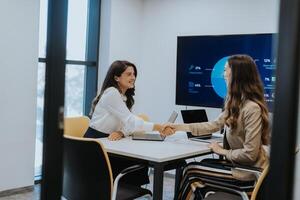 Young business women discussing in cubicle at the office photo