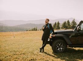 Young man relaxing by the terrain vehicle hood at countryside photo