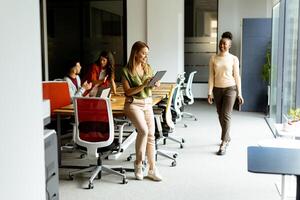 Young woman standing with digital tablet in front of her team at the office photo