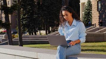 Business woman employer manager work online studying with computer sitting in city outdoors. Girl student typing laptop browsing web service sit on building company background busy with email in net photo