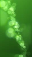 Vertical video - defocused green bokeh lights background. This elegant motion animation with sphere bokeh particles is full HD and looping. Suitable as an abstract St Patrick's Day background.