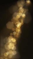 Vertical video - defocused golden bokeh lights background. This elegant motion background animation with hexagonal lens blur bokeh particles is full HD and a seamless loop.