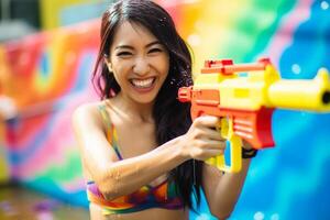 ai generado un mujer jugando agua pistola a Songkran día con generativo ai foto