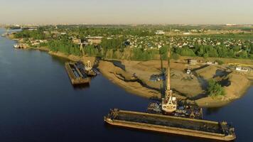 Bird's-eye view. Scene.The river on which there are ships for construction with cargo on them and a bright city with green summer trees against a blue sky is visible. photo