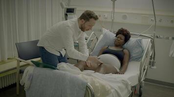 Young African Woman With Curly Hair Lying in Clinic Bed Talking to Physician video