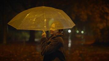 glücklich sorglos Frau Tanzen mit Regenschirm draußen im regnerisch Nacht video