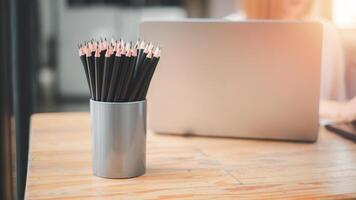 Many black pencils in basket on office desk. photo