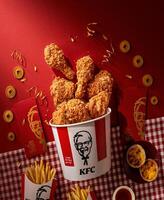 PAKISTAN, KARACHI DECEMBER 29, 2023 Crispy fried chicken and french fries on red background .KFC is popular fast food chain known as Kentucky Fried Chicken.Selective focus photo