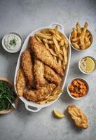 ai generado tradicional pescado y papas fritas con condimentos foto