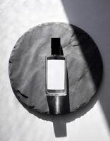 Mockup of galss transparent perfume bottle on stone plate and shadows photo