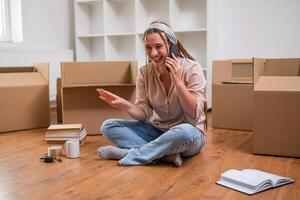 Modern ginger woman with braids talking on the phone while moving into her new apartment. photo