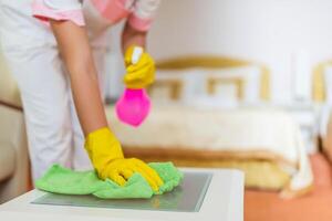 Close up image of hotel maid cleaning table in a room. photo