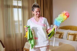 Beautiful hotel maid holding cleaning equipment. photo