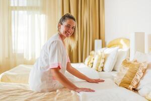 Beautiful hotel maid making bed in a room. photo