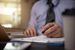 man hands with pen writing on notebook in the office.learning, education and work.writes goals, plans, make to do and wish list on desk.. photo