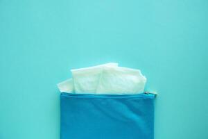 Sanitary napkin in women's fabric bag on blue background photo