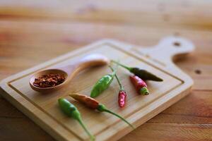 A spoon of cayenne pepper and fresh chilli on wooden background photo