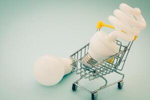 Fluorescent and LED light bulb with mini shopping cart photo